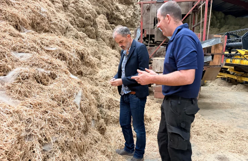 Sir Julian Smith with Nick Dale among straw in a farm shed at Riverside Farm